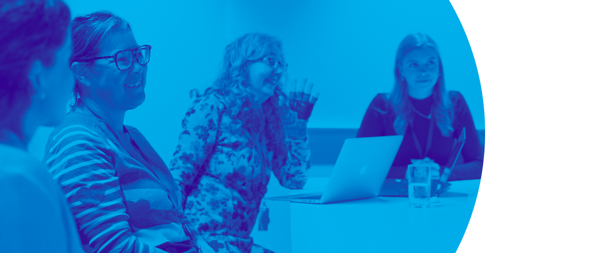 Four people sat in a meeting room having a pleasant discussion.